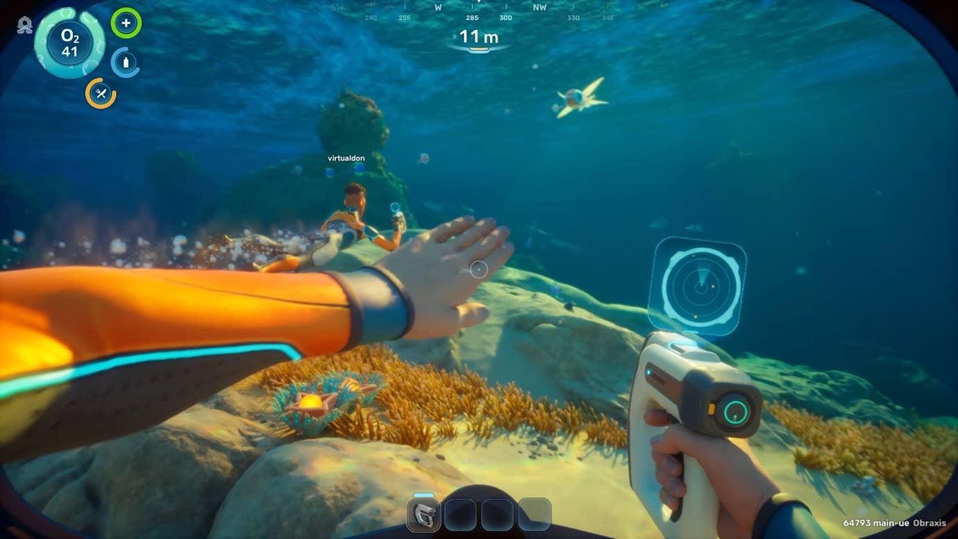 A player with a scanner in their hand swims through the shallows behind another player in co-op.